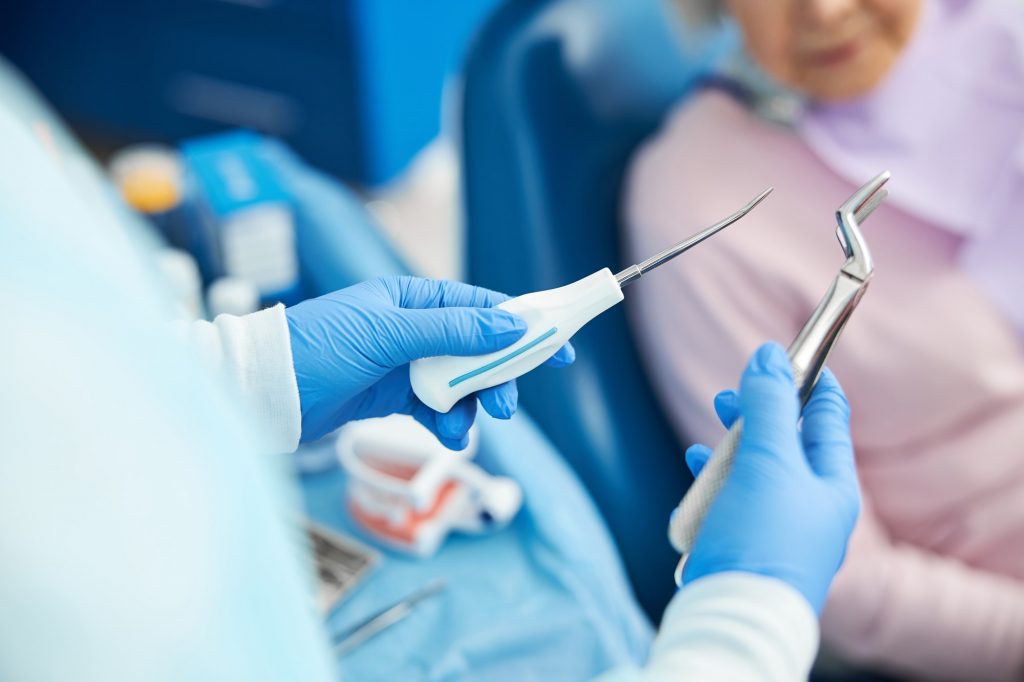 Dental male employee is demonstrating extraction instruments