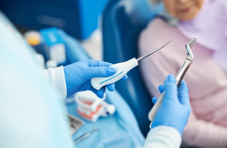Dental male employee is demonstrating extraction instruments