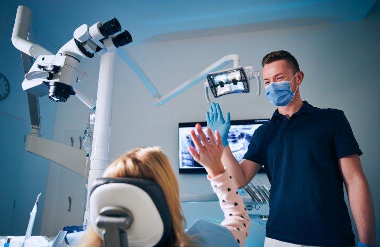 Dentist giving high-five to girl in modern dental surgery