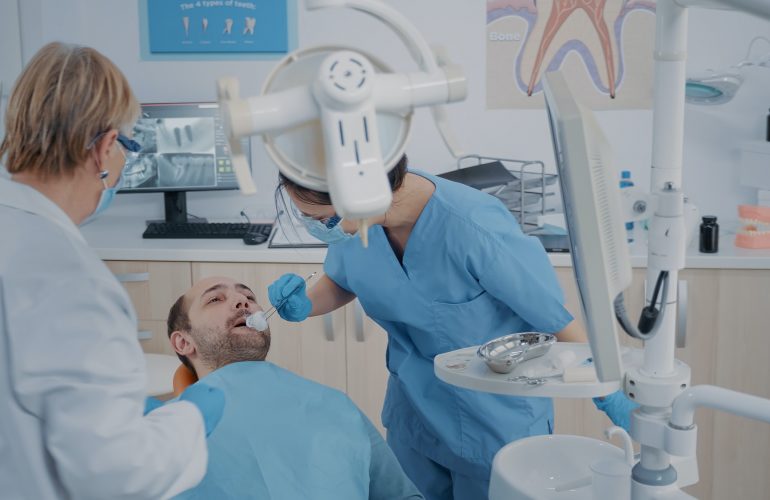 Dentistry team performing tooth extraction in stomatology cabinet