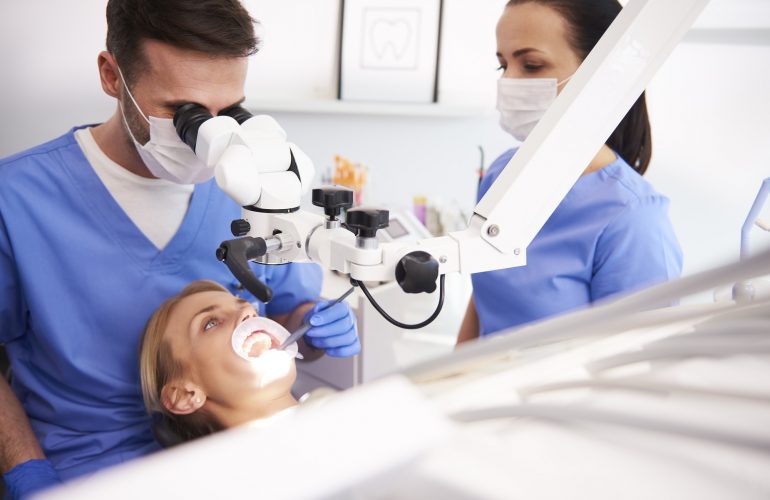 Male dentist looking through dental microscope